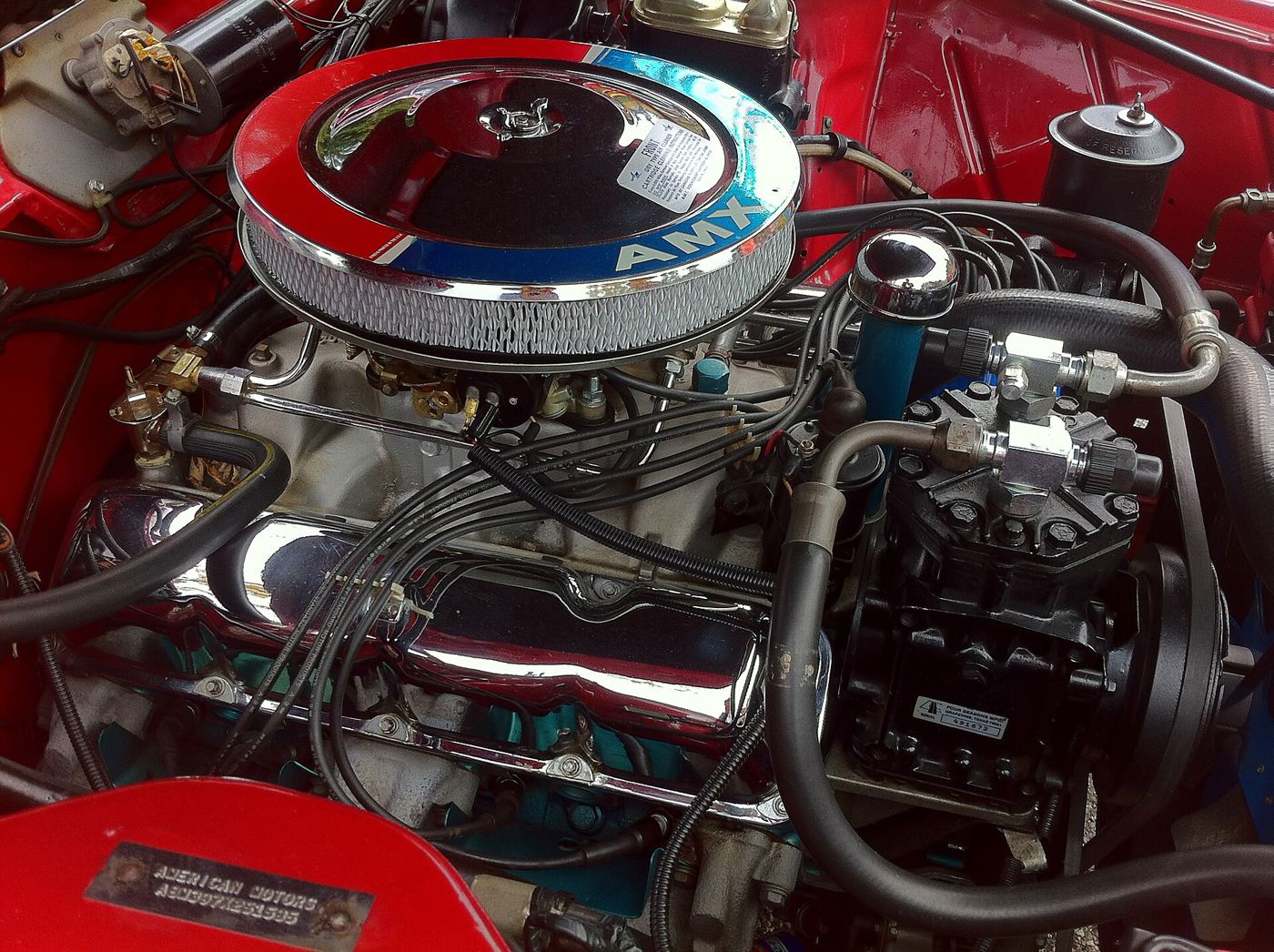 The 390 V8 in a red 1968 AMC AMX, with the AMX-lettered chrome air cleaner, blue engine paint and valve covers