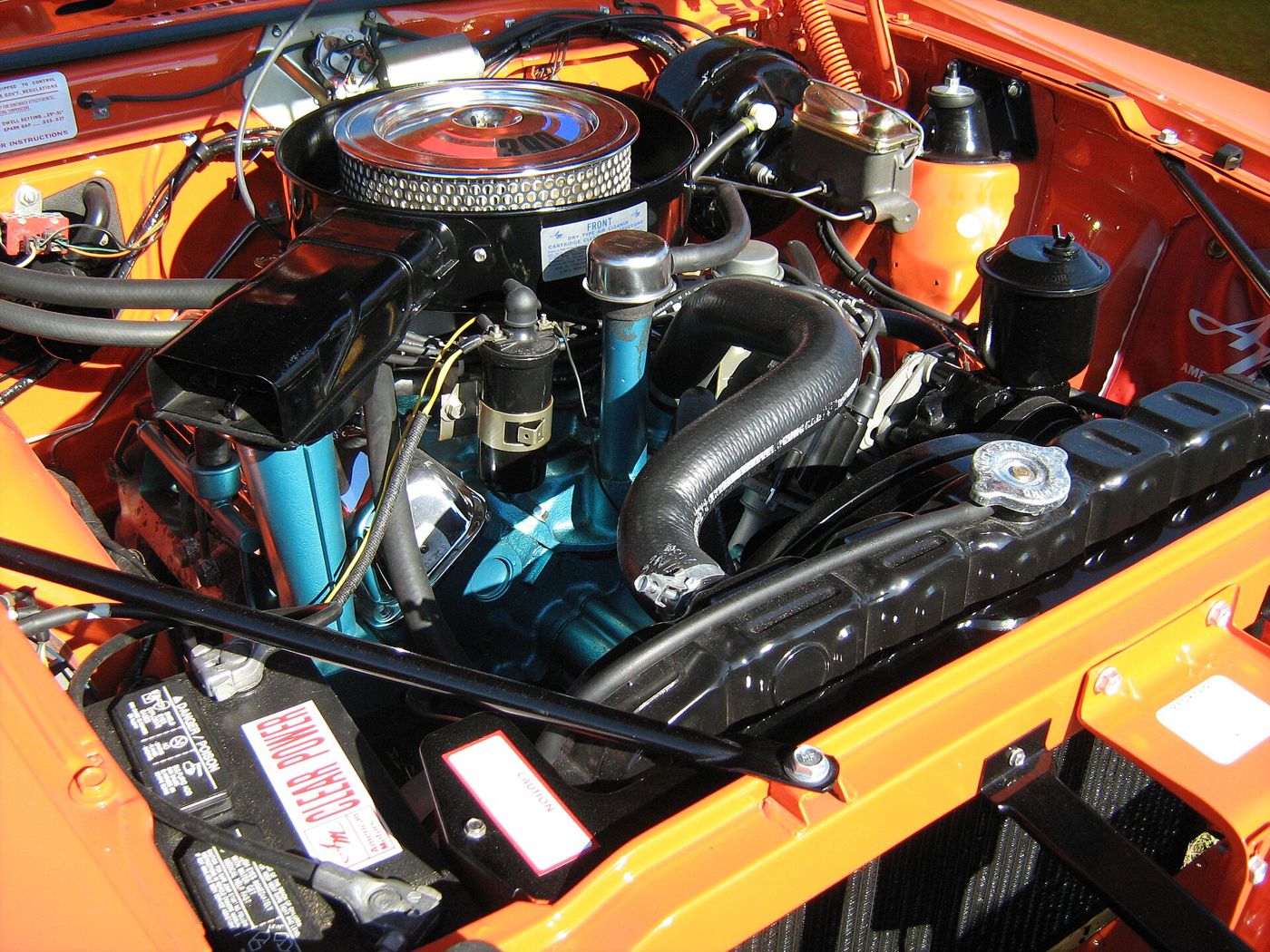 The 390 V8 in an orange 1970 AMC AMX, with blue engine paint and the ram-air ductwork