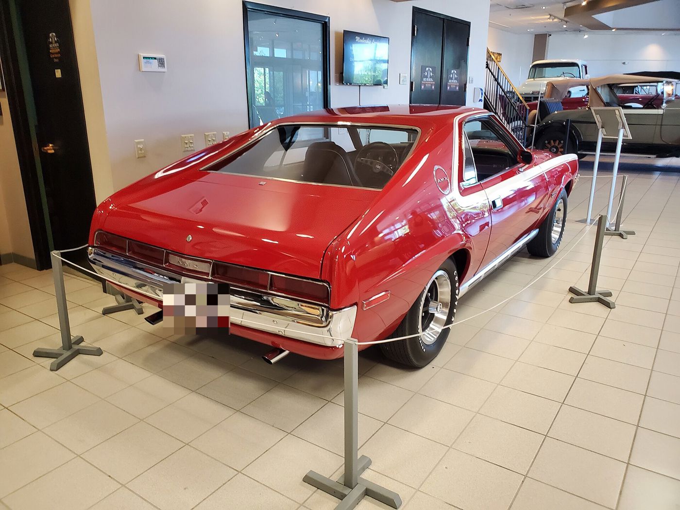 Rear three-quarter of a red 1970 AMC AMX showing the full-width taillamp panel with AMX lettering and dual exhausts