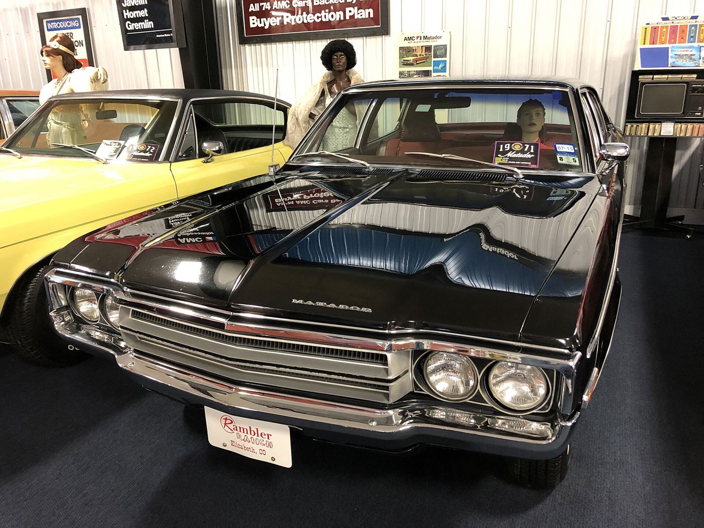 Black 1971 AMC Matador four-door sedan with MATADOR hood lettering, displayed in a museum with mannequins