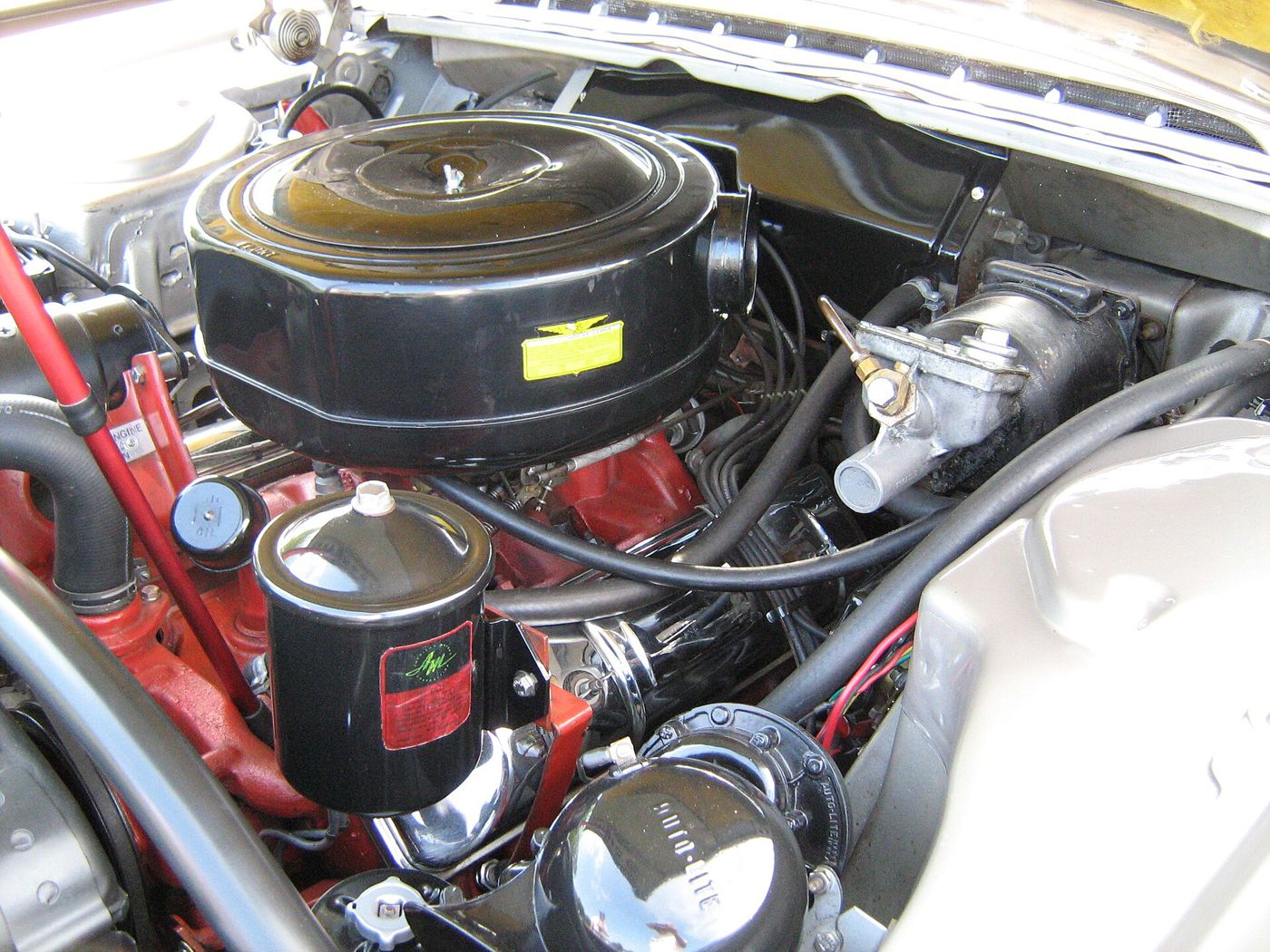 Engine bay of a 1957 Rambler Rebel with AMC's 327 V8, black air cleaner and red engine paint
