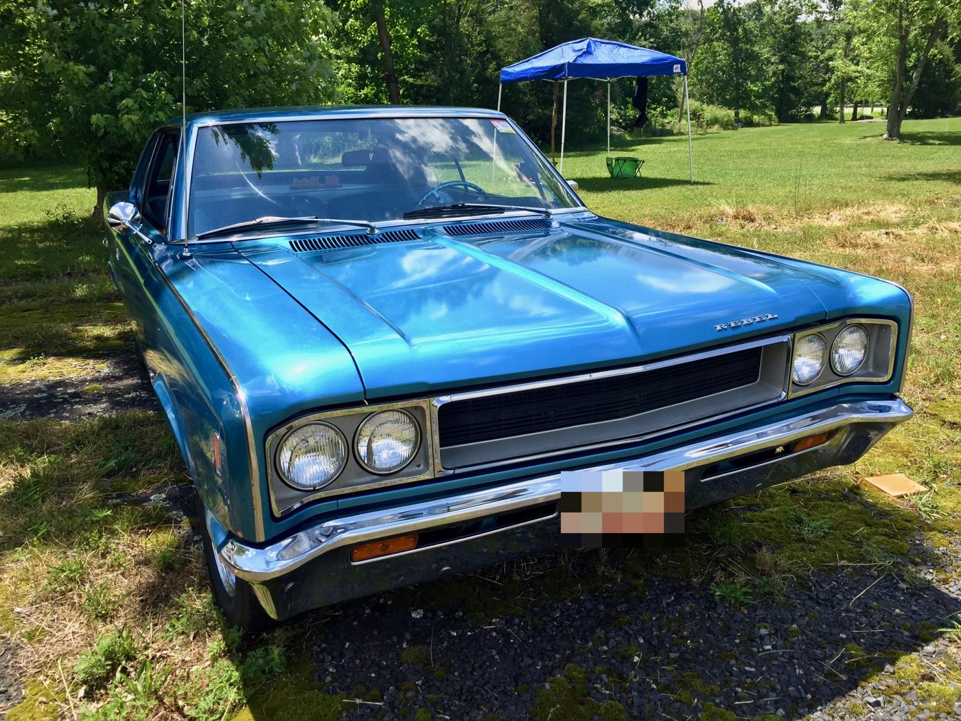 Front three-quarter view of a blue 1968 AMC Rebel 770 two-door hardtop parked on grass