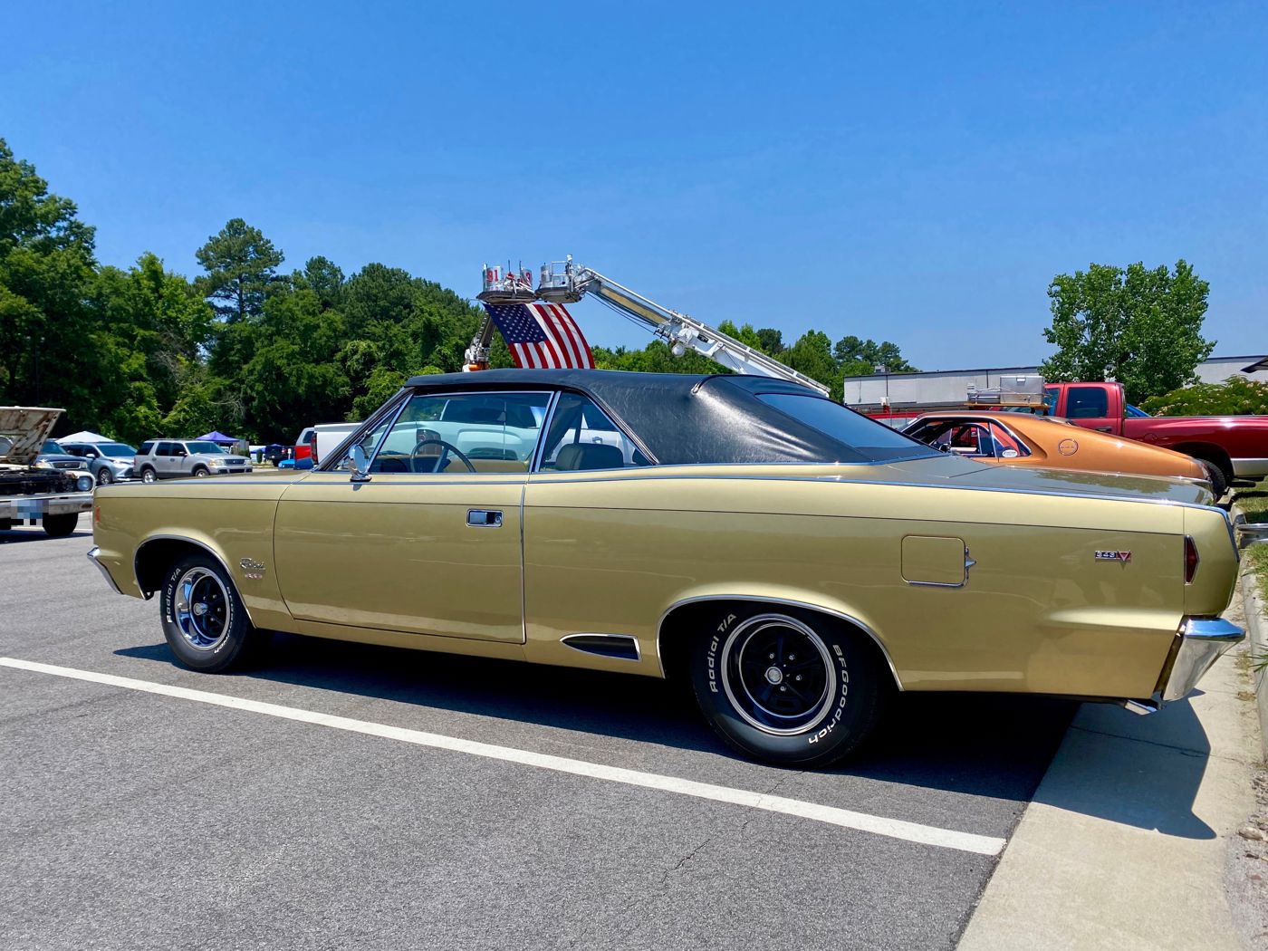 Side view of a gold 1968 AMC Rebel convertible with a black top, chrome wheels and a 343 V8 badge on the rear quarter