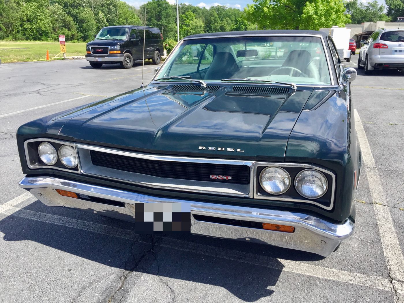 Front view of a dark-painted 1968 AMC Rebel SST two-door hardtop with a black vinyl roof, parked in a lot