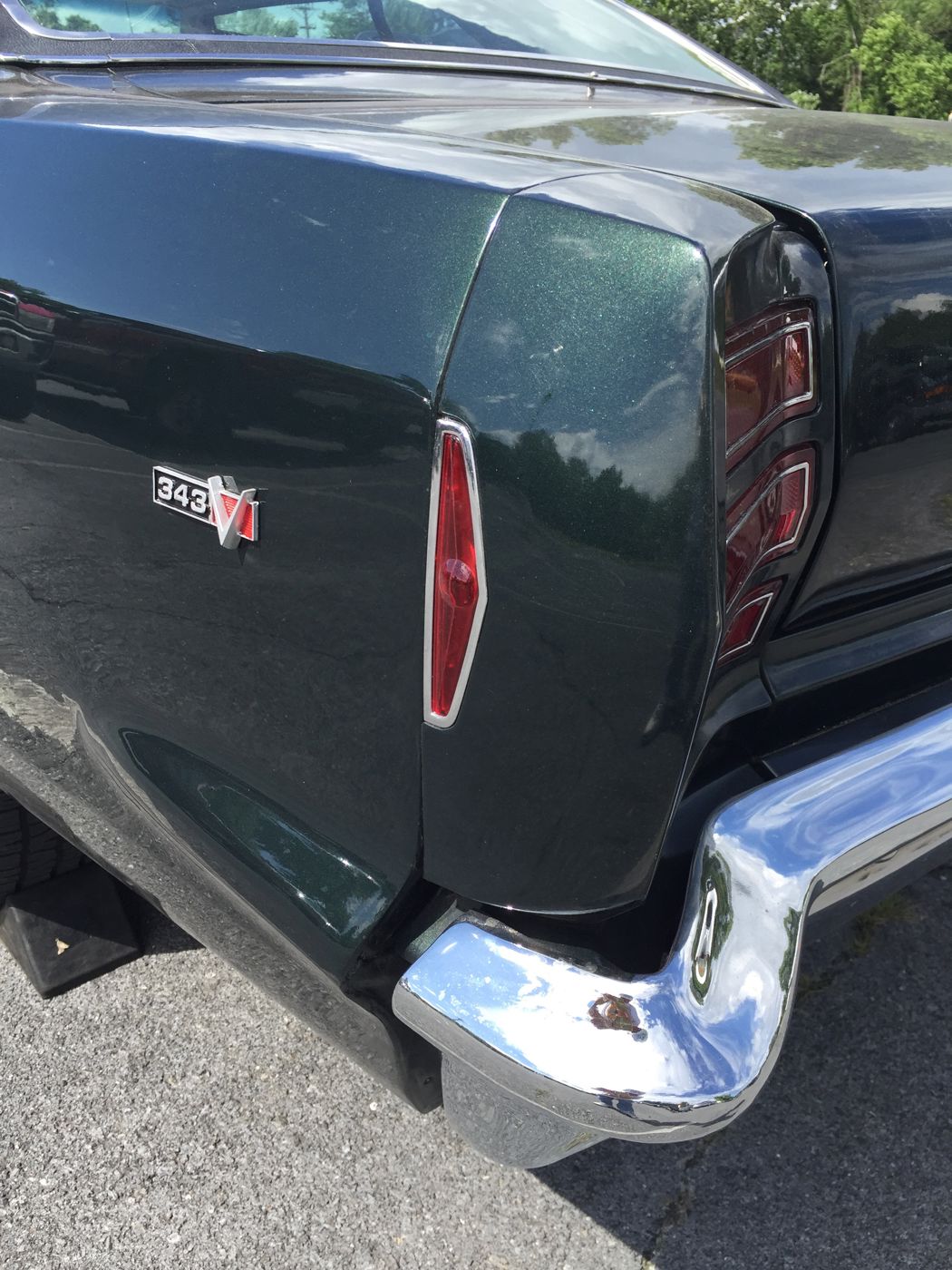 Close view of the rear quarter of a dark 1968 AMC Rebel hardtop showing the 343 V badge, the side marker lens, the stacked tail lamp and the chrome bumper end