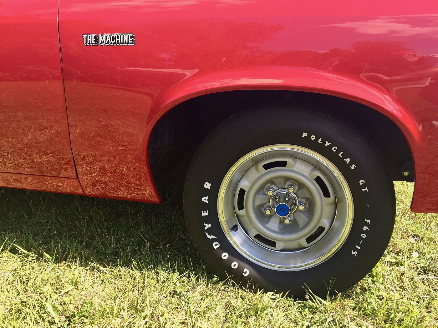 Close-up of the front fender of a red 1970 Rebel Machine with the THE MACHINE badge and its styled steel wheel