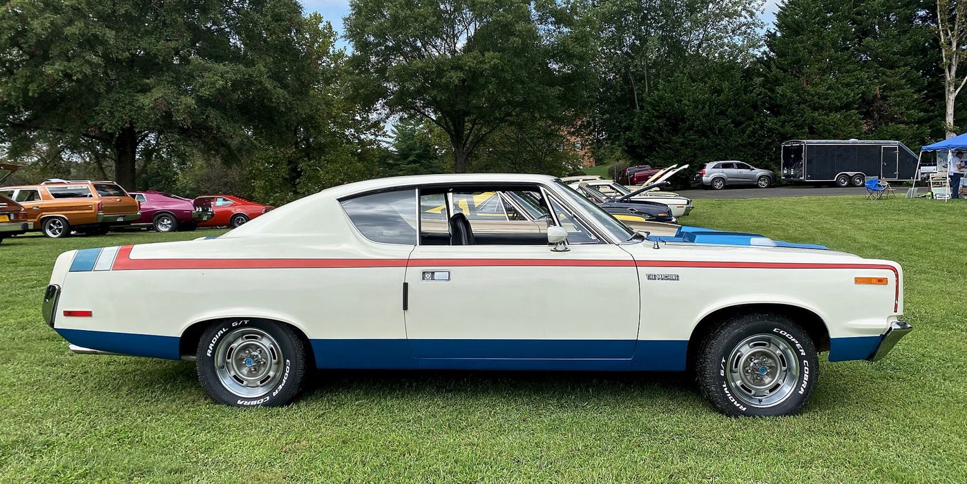 Side view of a white 1970 AMC Rebel The Machine with red, white and blue stripes, blue lower body and blue ram-air hood