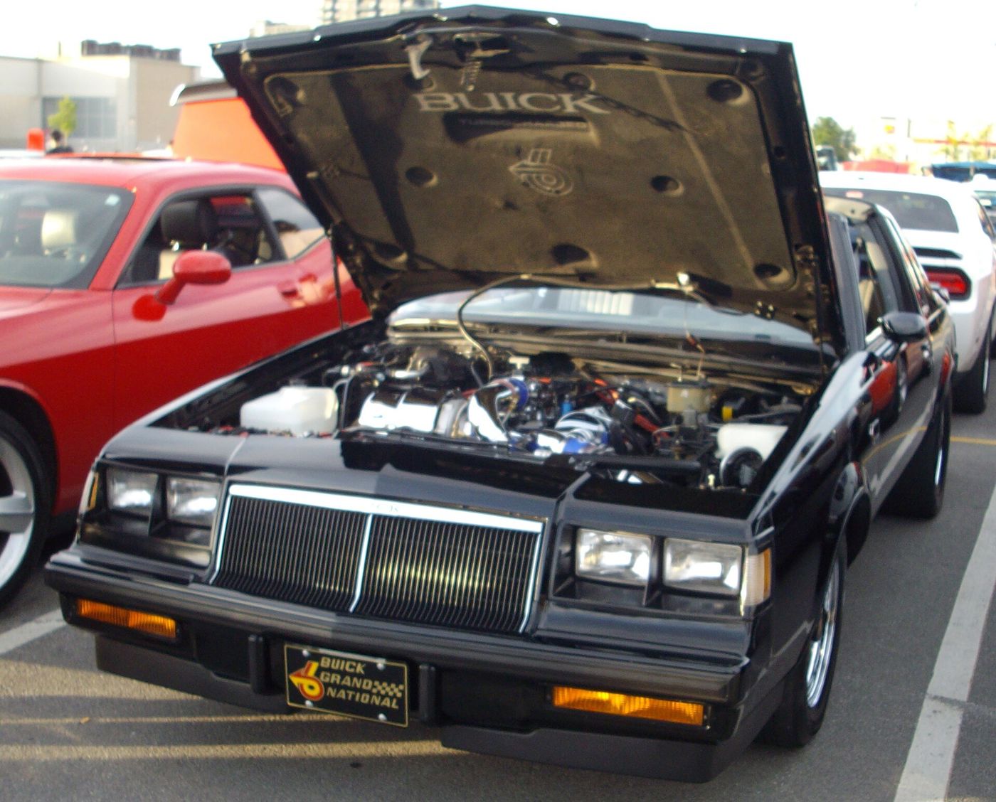 Black 1984 Buick Regal Grand National with hood raised, front view, at a car show
