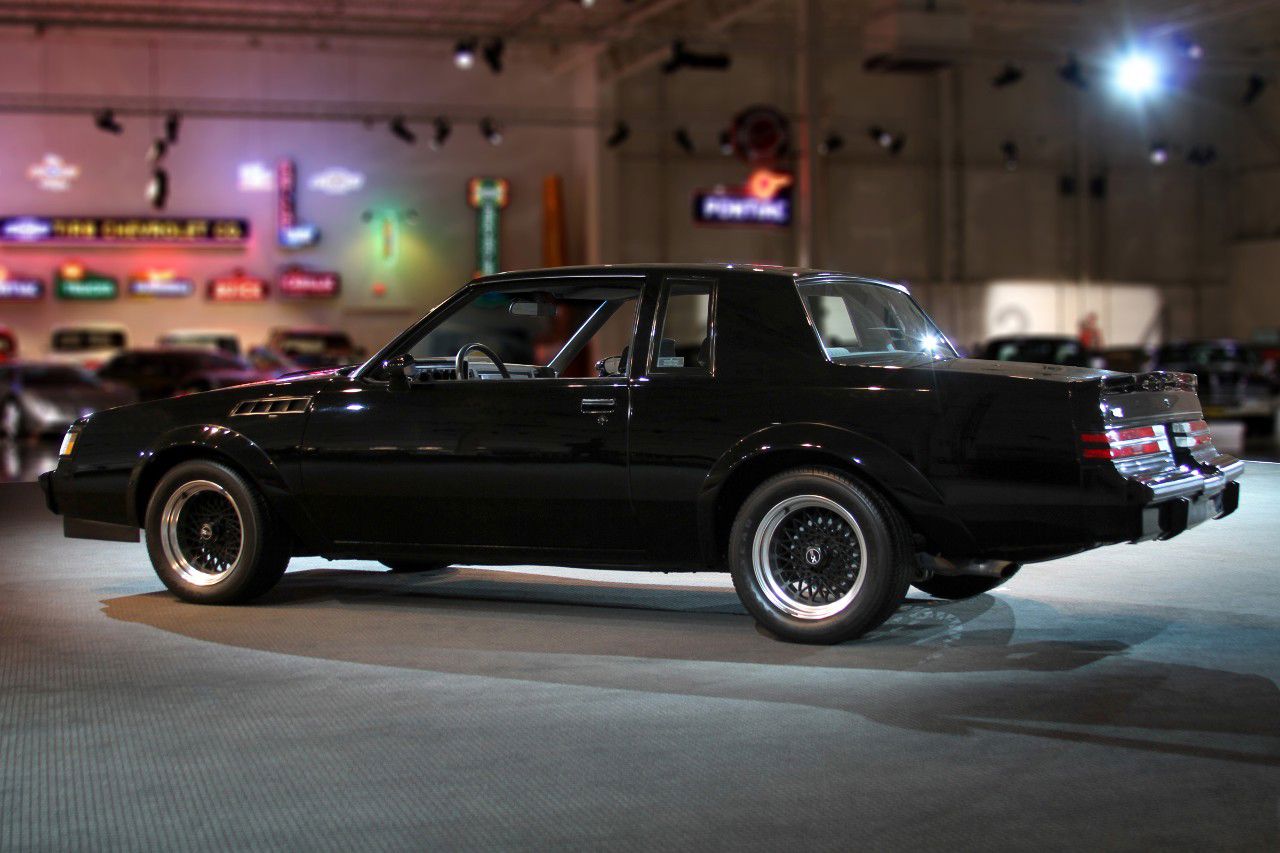 Black 1987 Buick GNX from the rear three-quarter, showing the rear spoiler and wide rear tires