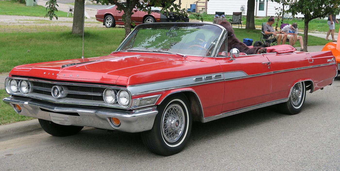 Red 1963 Buick Wildcat convertible with white side spear, front three-quarter, at a car show