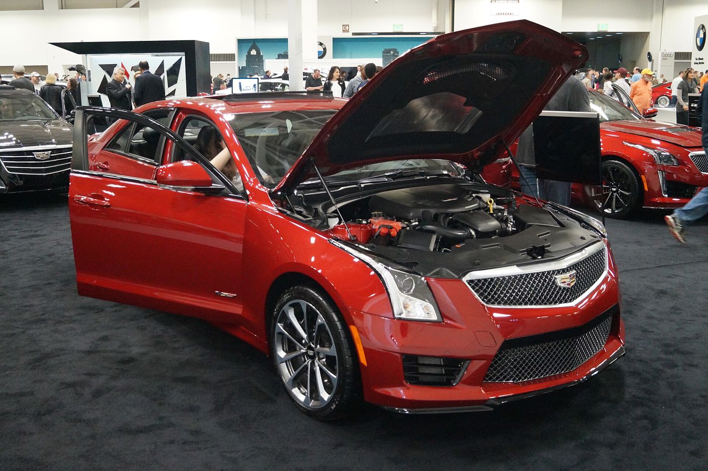 Red 2016 Cadillac ATS-V sedan with its hood up at an auto show