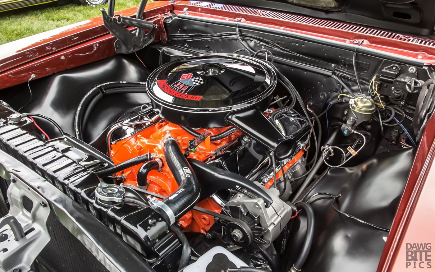 Orange 396 big-block V8 in a restored 1966 Chevelle SS 396 engine bay, its black air cleaner lid reading 396 Turbo-Jet 325 HP with the crossed-flags emblem