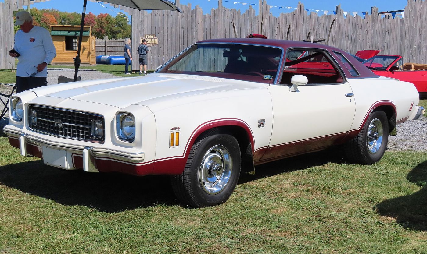 White 1974 Chevrolet Chevelle Laguna Type S-3 Colonnade coupe with burgundy lower-body paint and pinstripe, Laguna S-3 grille and pillar badges, 454 fender badge and Rally wheels, parked on grass at a car show