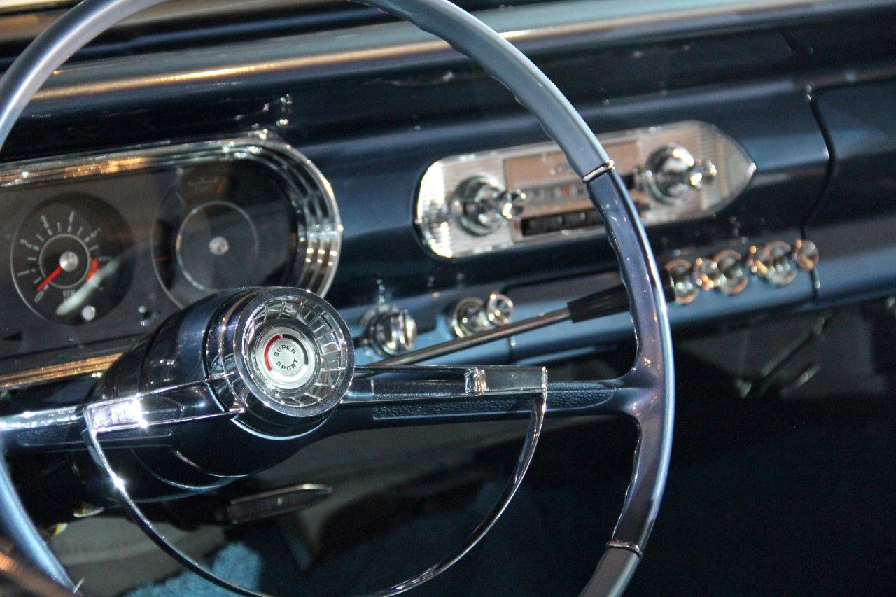 Dashboard of a 1963 Chevy II Nova SS with the Super Sport horn button, horn ring, column shift lever, round instrument pods including a tachometer, and the push-button radio