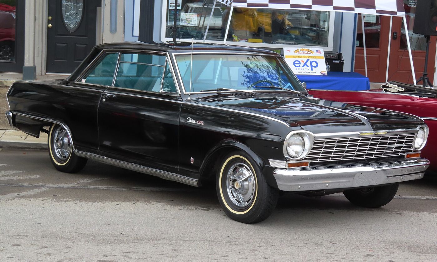 Black 1964 Chevrolet Chevy II Nova SS two-door hardtop at a downtown car show, front three-quarter, with Nova SS fender script, SS wheel covers and whitewall tyres