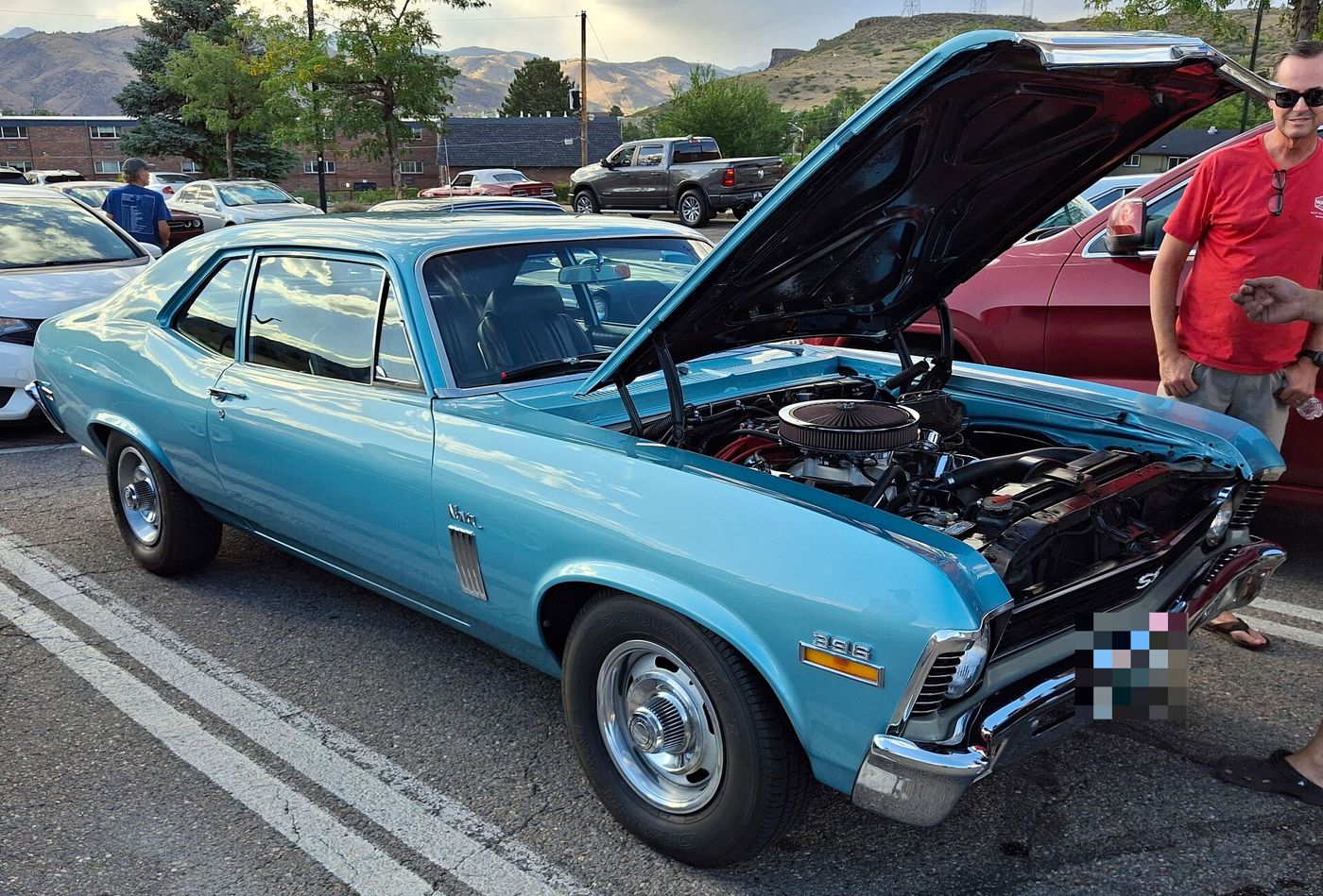 Light blue 1968 Chevy II Nova SS coupe at an evening car show, front three-quarter with the hood raised, showing the SS grille badge, 396 fender badge, simulated side vents and Rally wheels