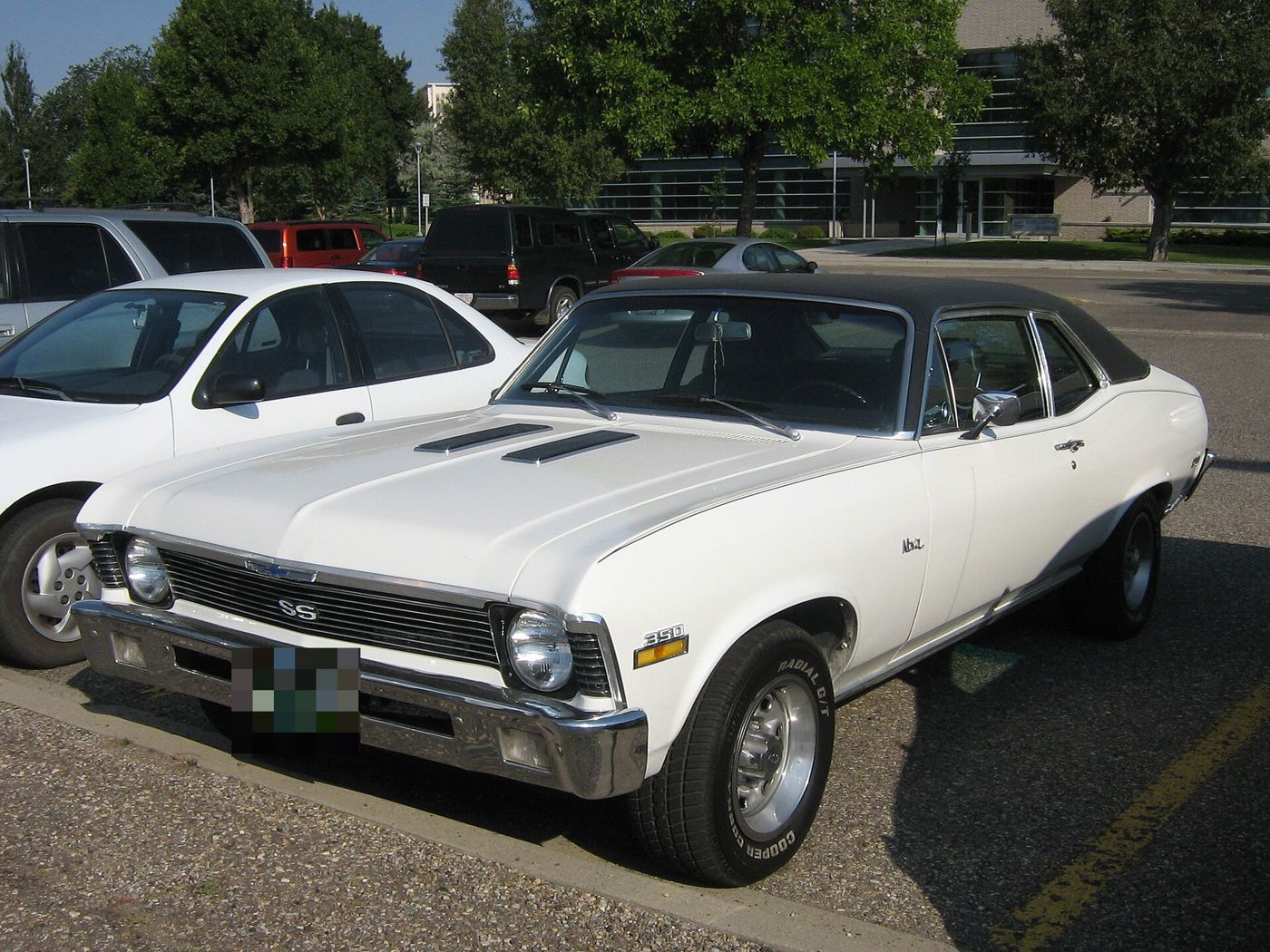 White 1971 Chevrolet Nova SS coupe with a black vinyl roof in a parking lot, front three-quarter, with SS grille badge, 350 fender badge and twin hood inserts