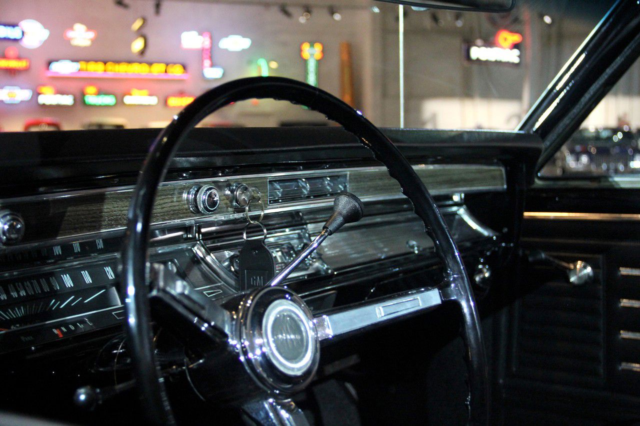 Interior of a 1967 Chevrolet El Camino SS with the thin-rim steering wheel, column shift lever, horizontal speedometer and woodgrain-trimmed dashboard