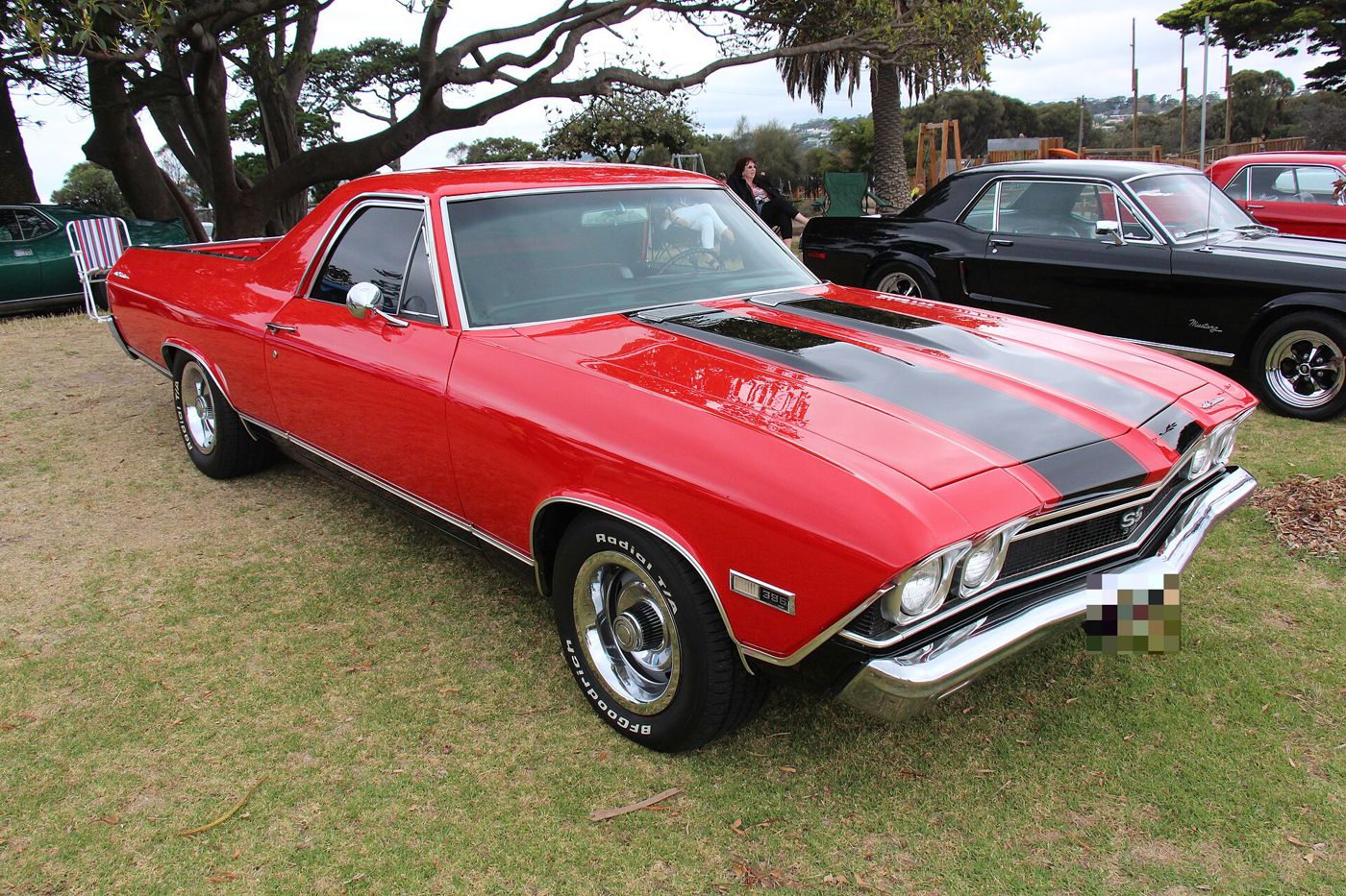 Red 1968 Chevrolet El Camino SS 396 on grass at an Australian car show, front three-quarter, with black hood stripes, SS grille badge and 396 fender badge