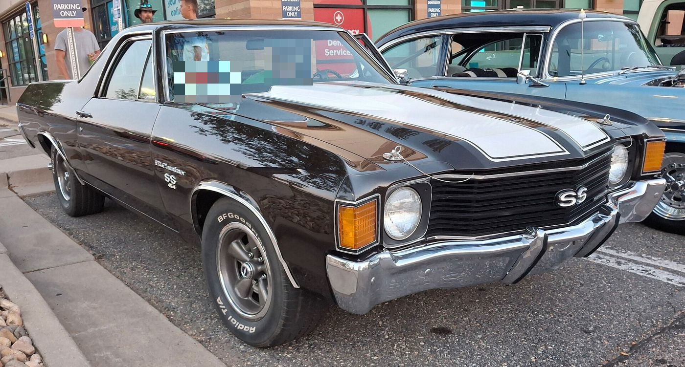 Black 1972 Chevrolet El Camino SS 454 at an evening car show, front three-quarter, with white hood stripes, hood pins, SS grille badge and El Camino SS 454 fender badges