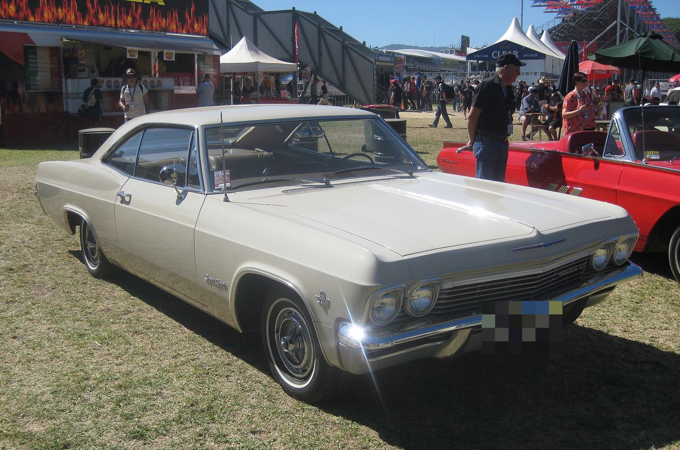Cream 1965 Chevrolet Impala SS two-door hardtop at an outdoor show, front three-quarter, with Super Sport script on the front fender and Impala SS grille badge