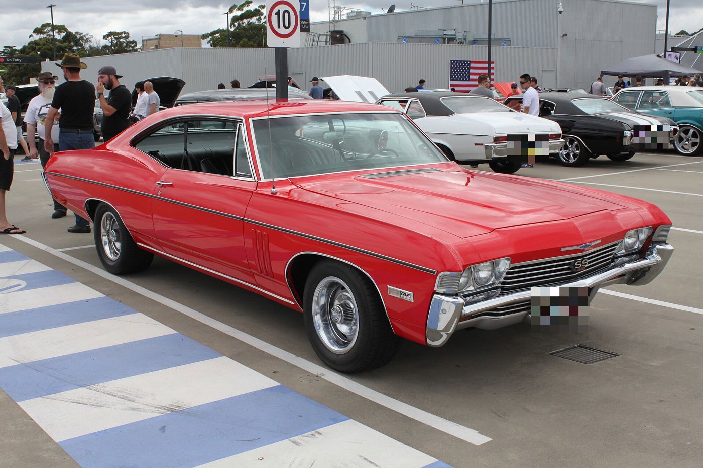 Red 1968 Chevrolet Impala SS 427 fastback hardtop in a car-show parking lot, front three-quarter, with SS 427 grille and front-fender badges