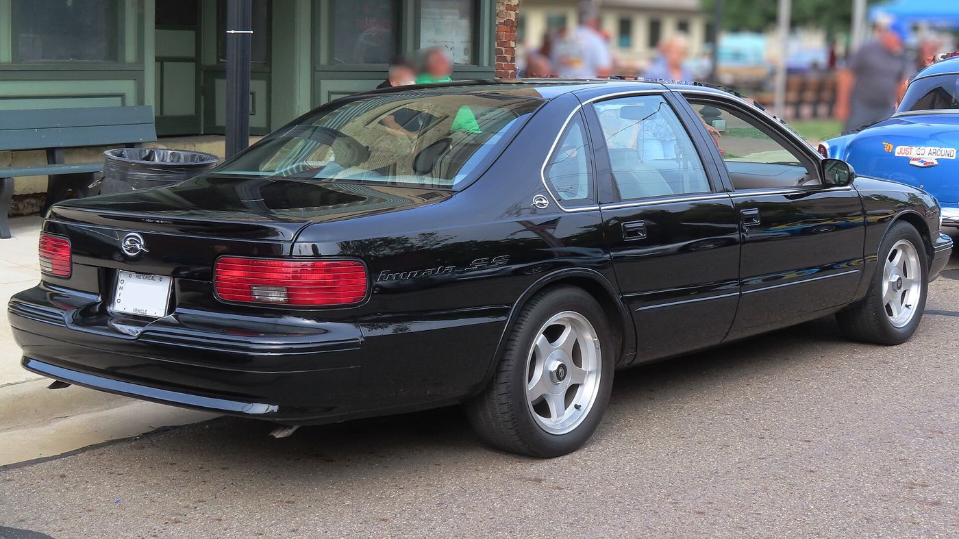 Black 1996 Chevrolet Impala SS sedan from the rear three-quarter, showing the Impala SS script on the rear quarter panel, the leaping-impala emblem on the trunk and rear pillar, and the five-spoke alloy wheels