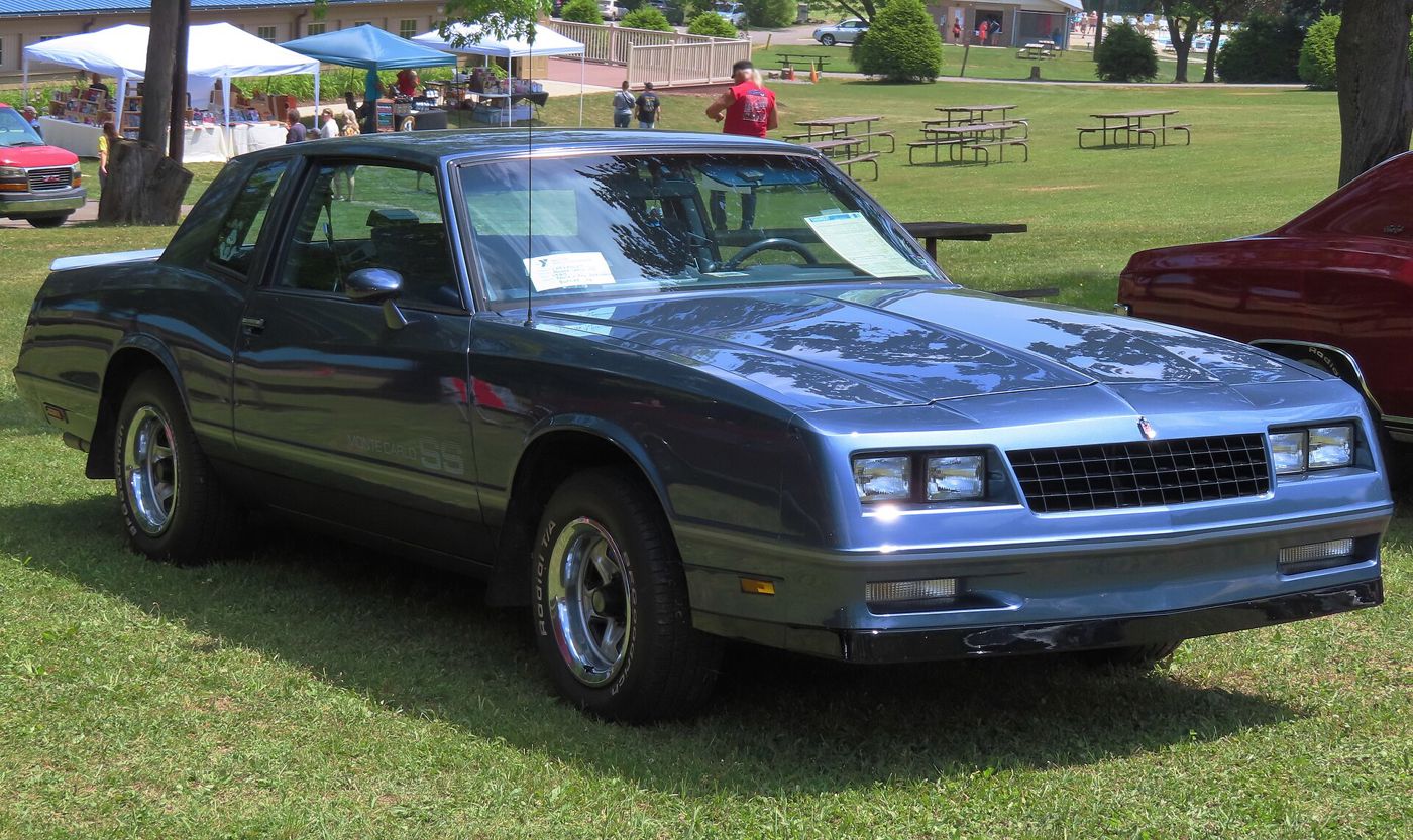 Blue 1984 Chevrolet Monte Carlo SS at an outdoor car show, front three-quarter, with the aero nose, Monte Carlo SS door lettering and Rally wheels