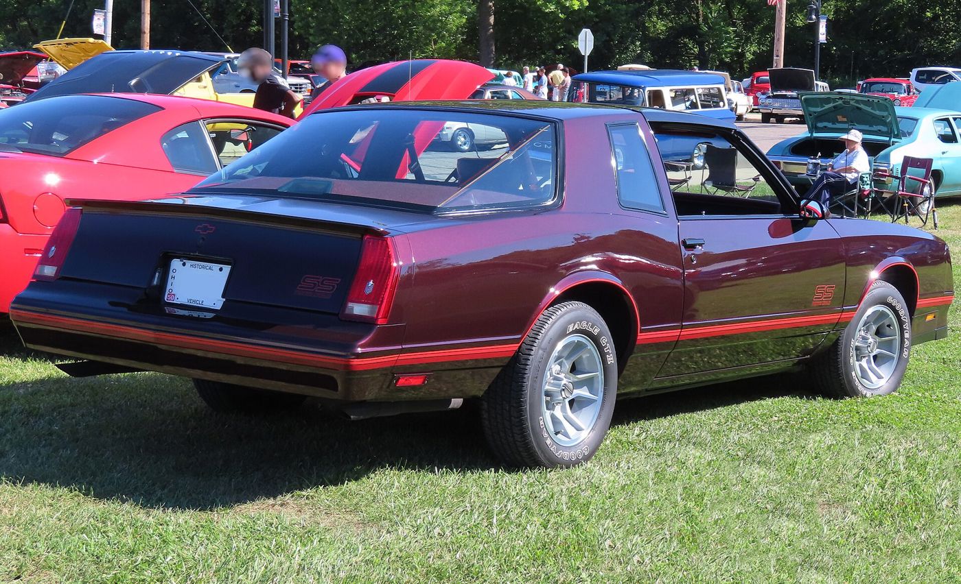 Rear three-quarter of a dark maroon 1987 Chevrolet Monte Carlo SS Aerocoupe showing the large curved rear glass, short decklid with spoiler, and SS badges on the decklid and door
