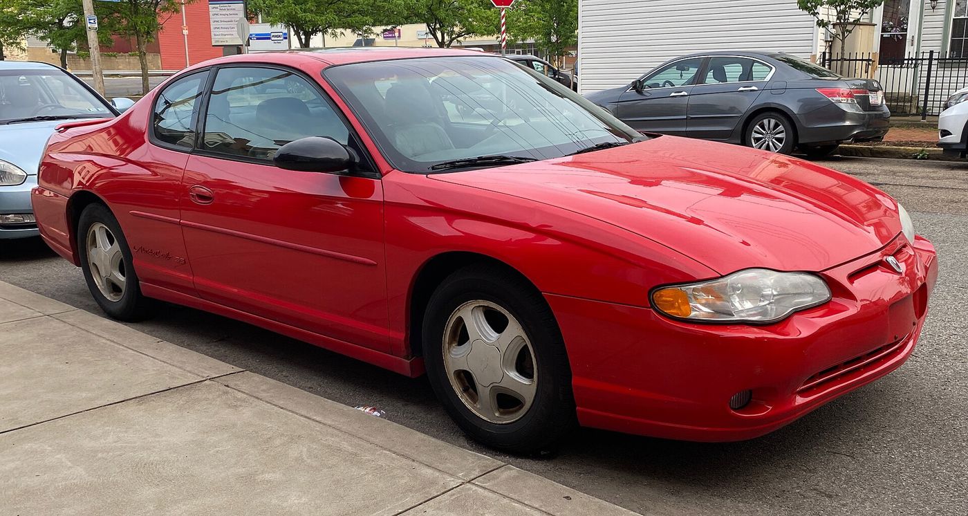 Torch Red 2000 Chevrolet Monte Carlo SS coupe parked on a city street, front three-quarter, with Monte Carlo SS script on the door