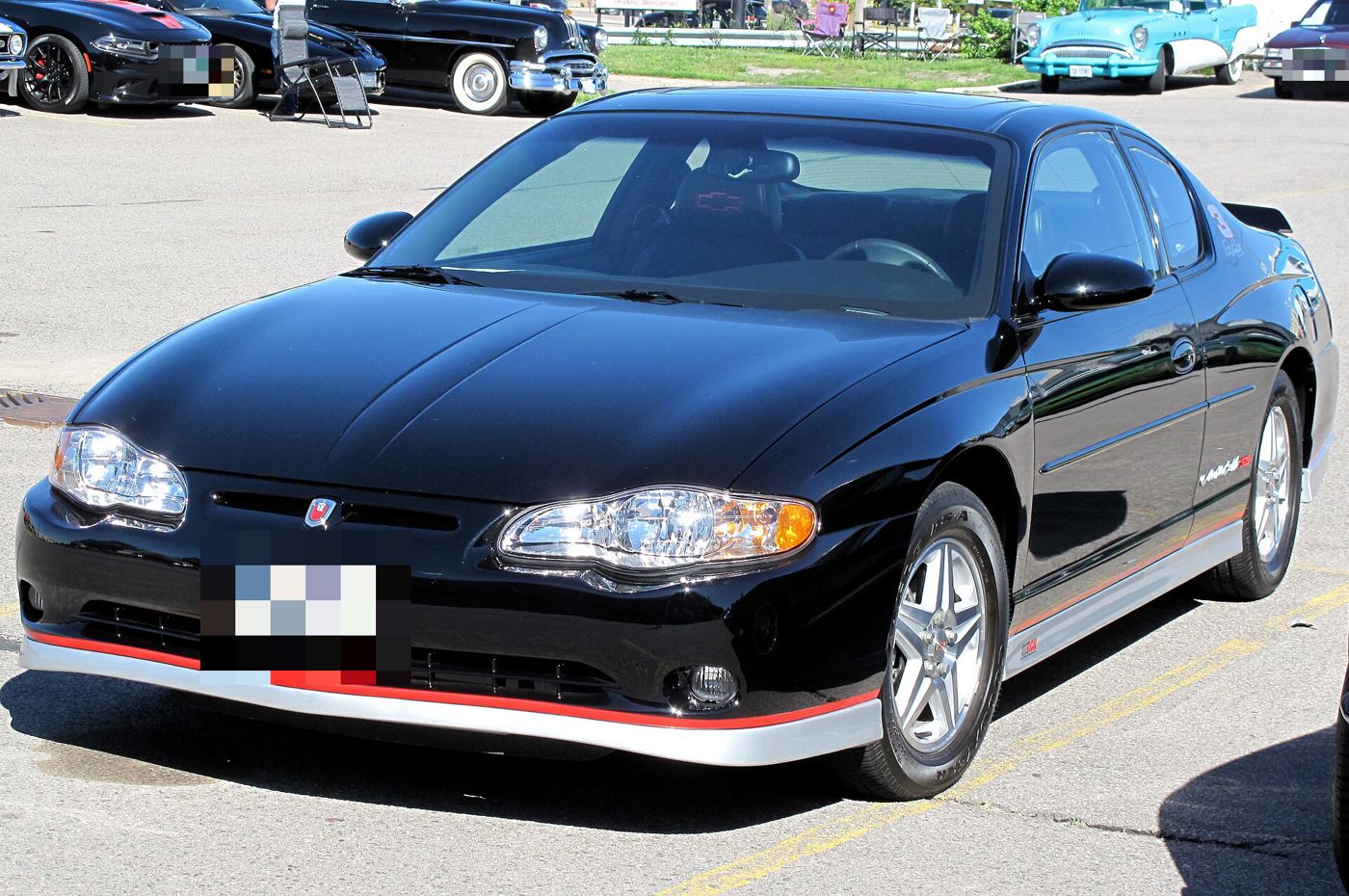 Black 2002 Chevrolet Monte Carlo SS Dale Earnhardt signature edition with silver lower body trim, red pinstripe and the number 3 on the rear quarter window, parked at a car show