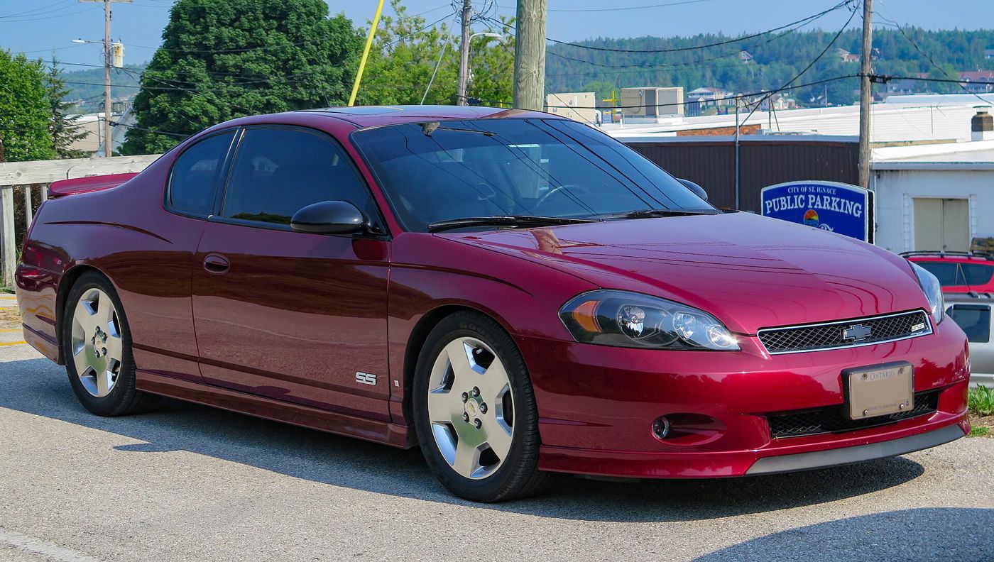 Red Jewel Tintcoat 2007 Chevrolet Monte Carlo SS coupe in a parking lot, front three-quarter, with the SS grille badge, SS door badge and 18-inch polished wheels