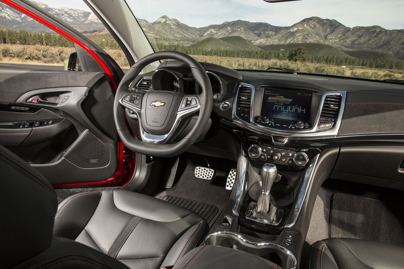Driver-side view of the 2014 Chevrolet SS cabin with black leather sport seats, the steering wheel, the center touch screen and the automatic shifter
