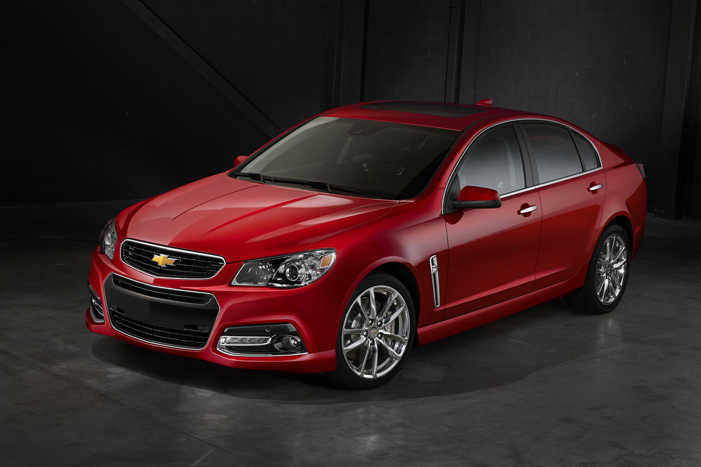 Red 2015 Chevrolet SS sedan photographed in a dark studio from the front three-quarter