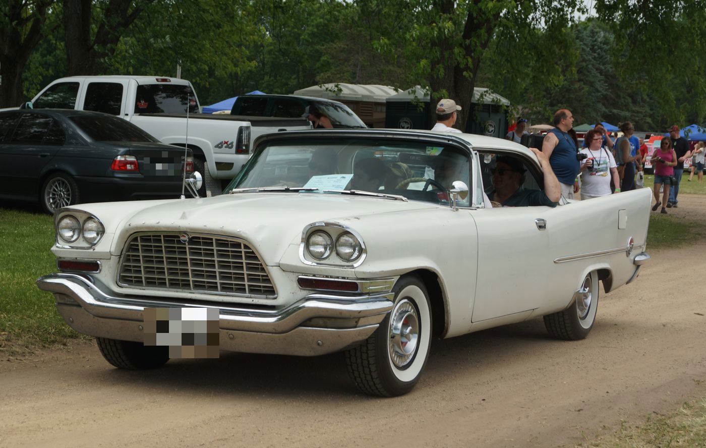 White 1957 Chrysler 300C with its large trapezoid grille and quad headlamps, at an outdoor car show