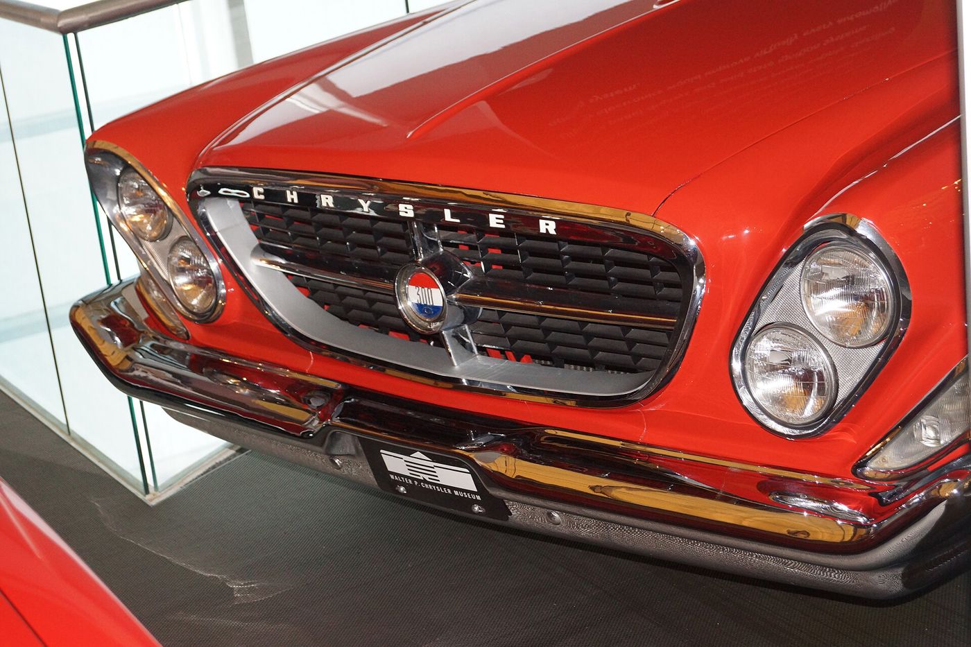 Close view of the grille, 300 medallion and slanted twin headlamps of a red 1961 Chrysler 300G on museum display