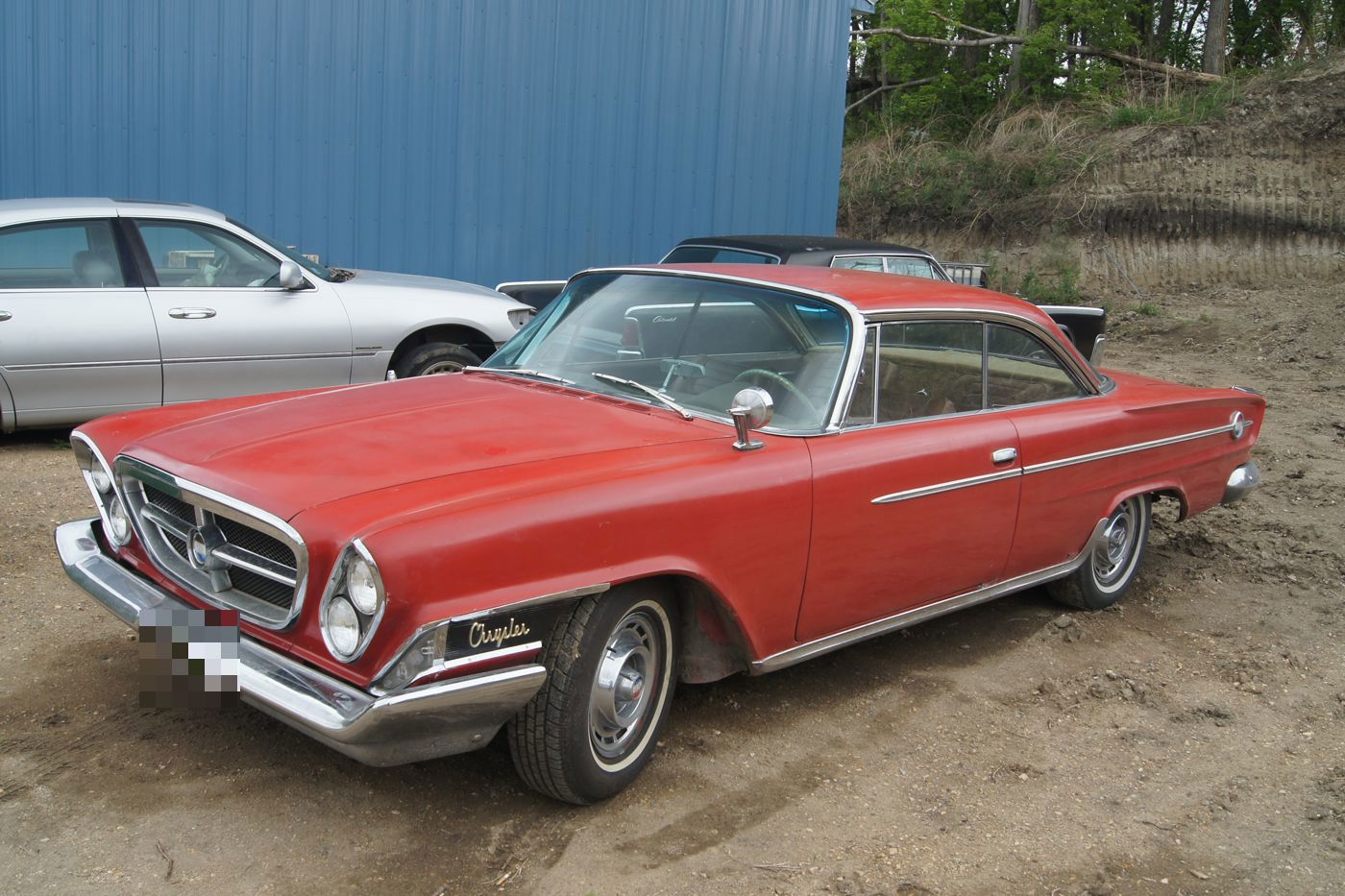 Red 1962 Chrysler 300H two-door hardtop with its canted headlamps, parked on gravel