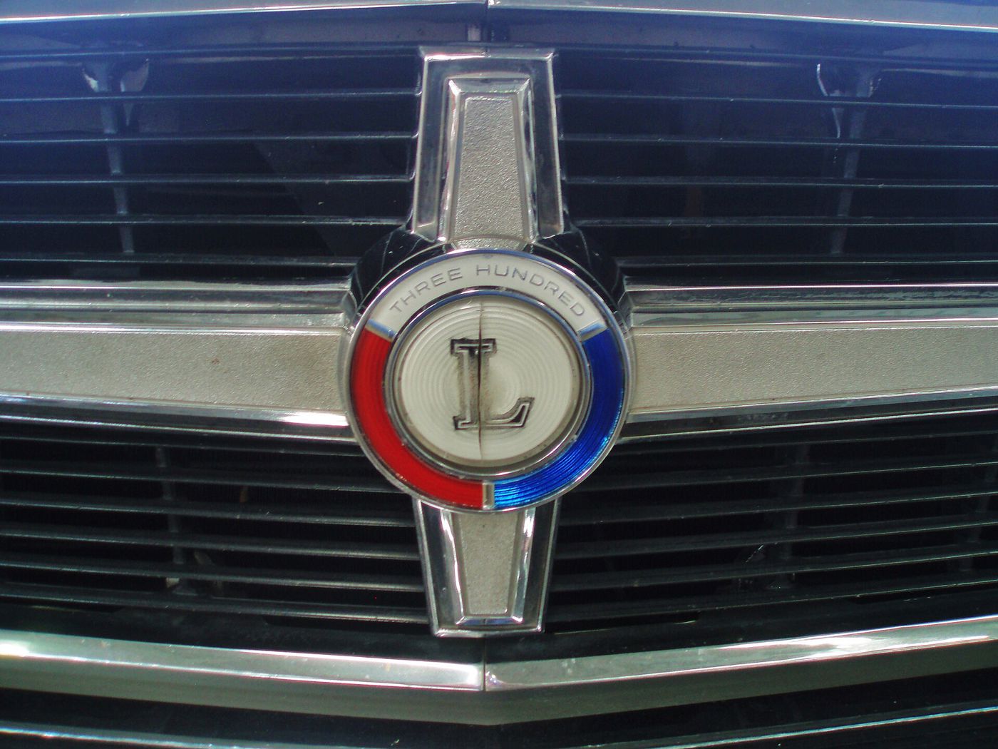 Close-up of the red, white and blue grille medallion reading THREE HUNDRED around a large L