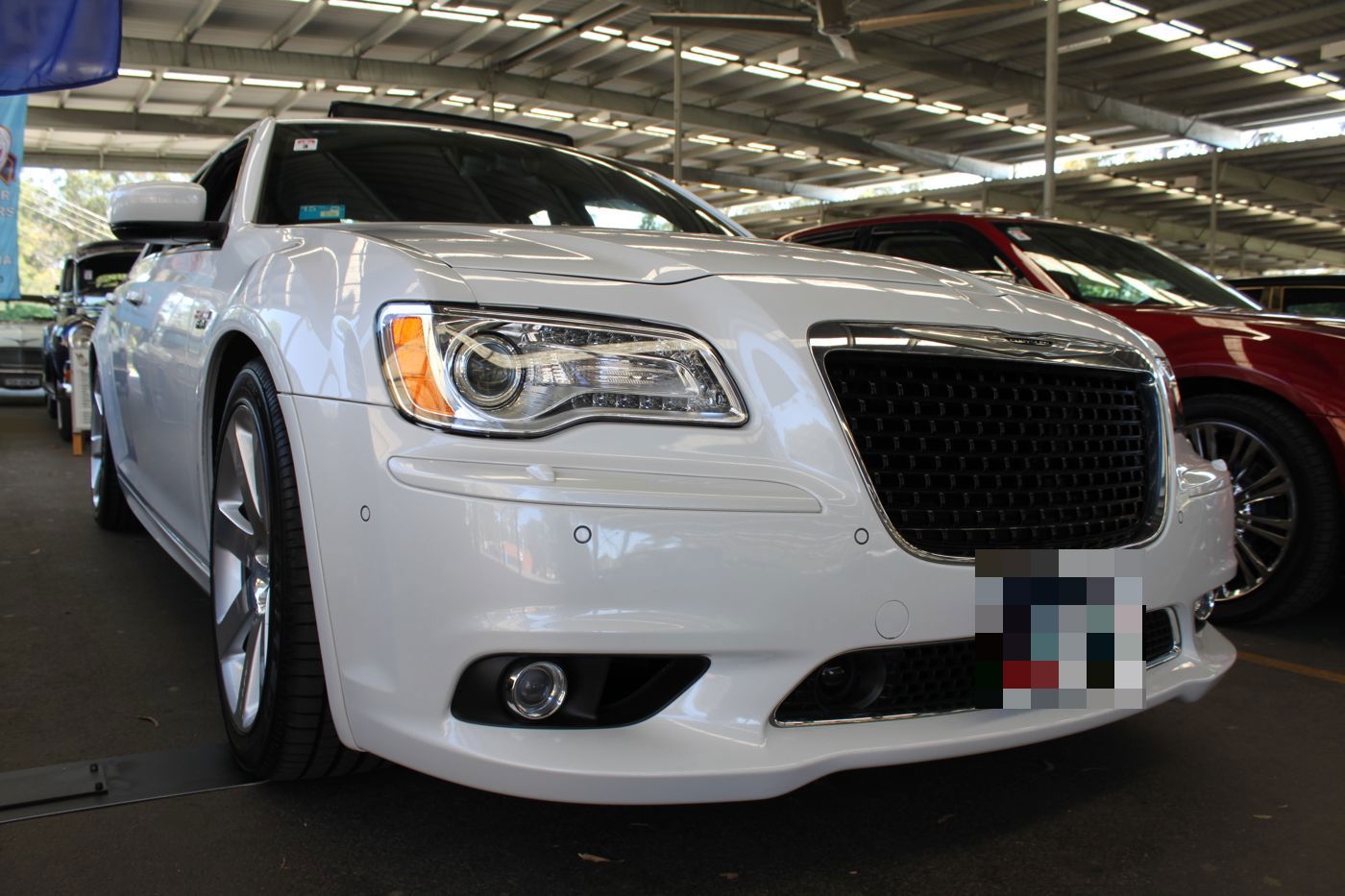 White second-generation Chrysler 300 SRT8 seen close from the front, with its black mesh grille and projector headlamps