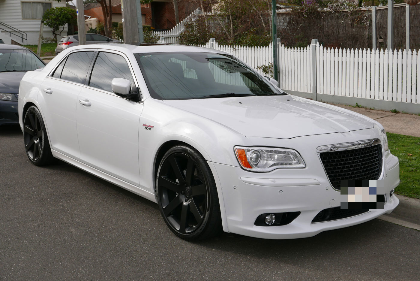 White 2013 Chrysler 300 SRT8 parked in a residential street, front three-quarter, showing the 6.4 badge on the front fender
