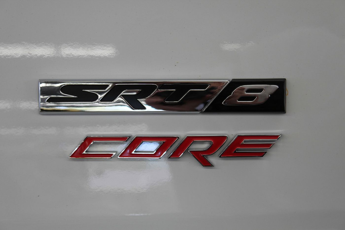 Chrome and red SRT8 badge above a red CORE badge on white paintwork