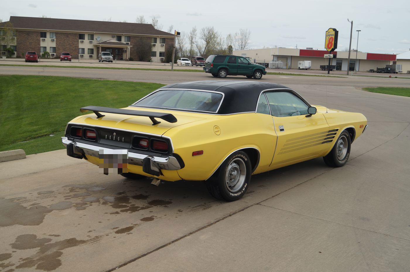 Yellow 1973 Dodge Challenger with black vinyl roof, rear wing spoiler and Rallye fender vents, rear three-quarter