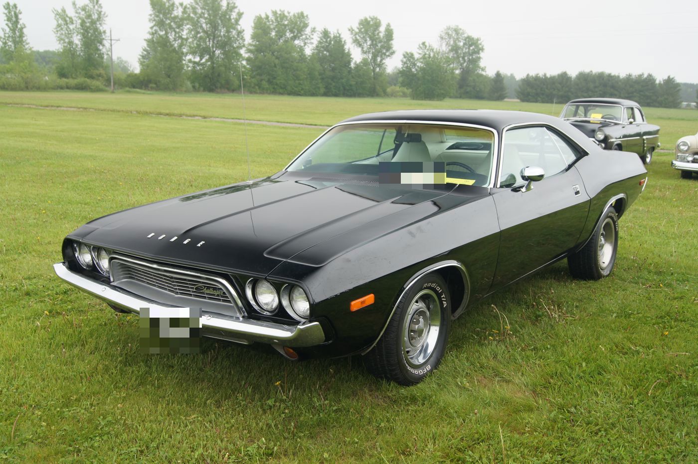 Black 1974 Dodge Challenger on grass, front three-quarter, showing the 1972–74 grille and the large 1974 bumper guards