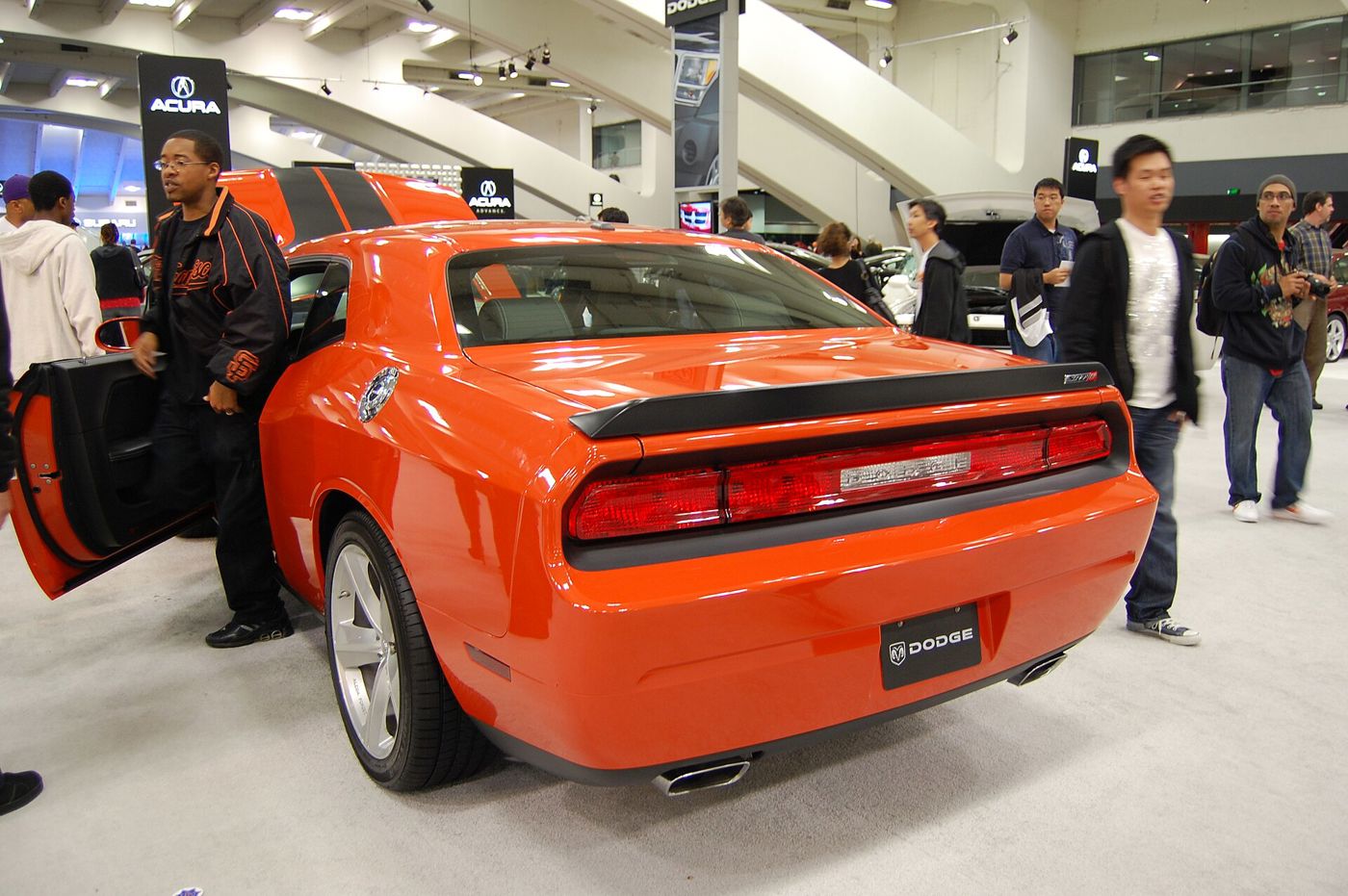 Orange 2009 Dodge Challenger SRT8 from the rear three-quarter, showing the full-width taillamps and decklid spoiler