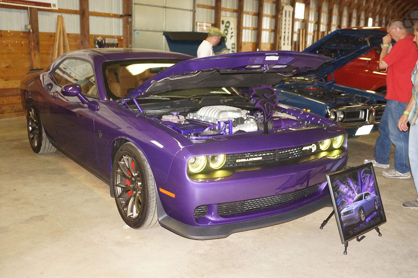 Purple 2015 Dodge Challenger SRT Hellcat at an indoor show with the hood raised, showing the supercharger