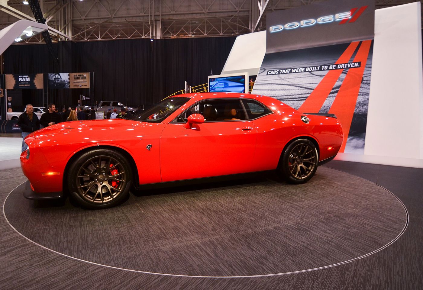 Red 2015 Dodge Challenger SRT Hellcat on a turntable at an auto show, with the 2015 split grille and halo headlamps
