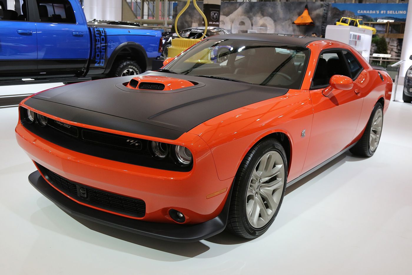 Orange 2020 Dodge Challenger R/T 50th Anniversary Edition with black hood and Shaker scoop, on an auto show floor