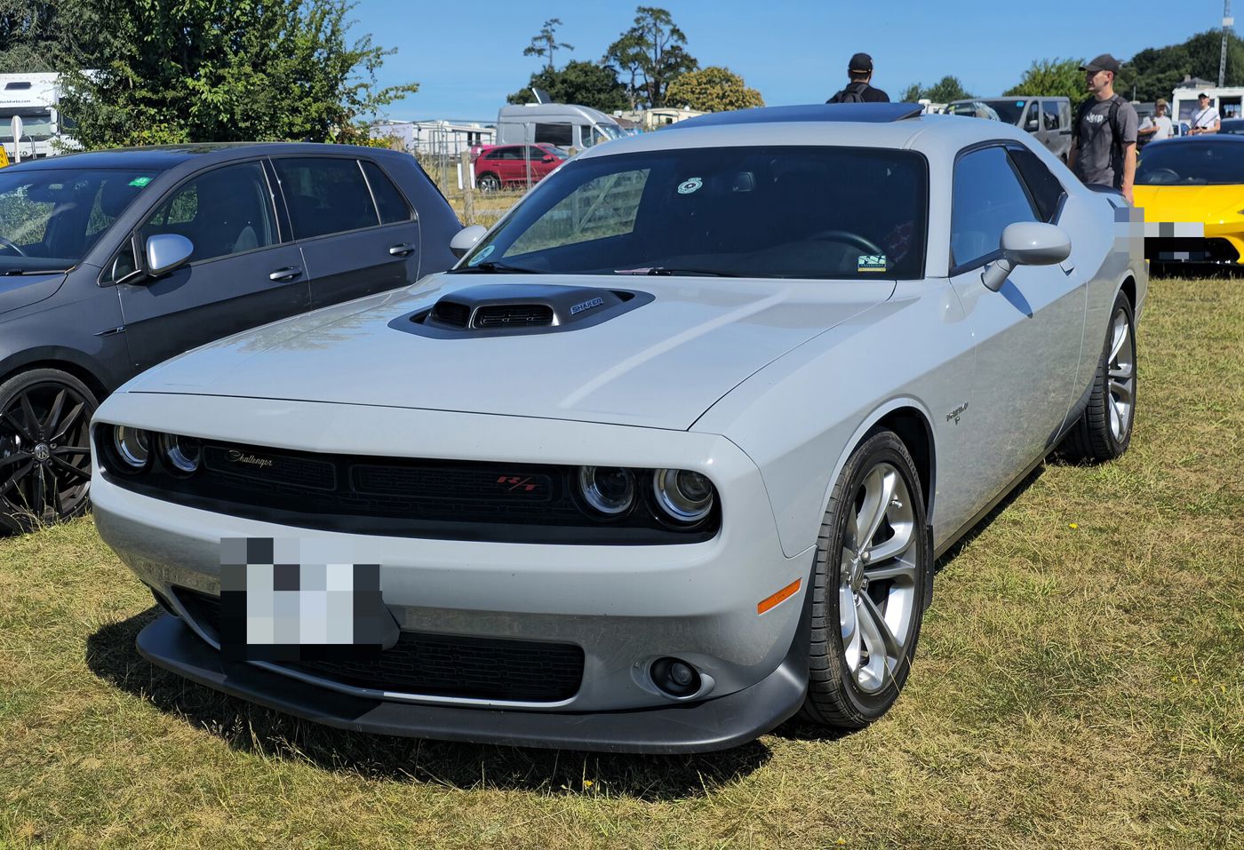 Silver 2023 Dodge Challenger R/T with Shaker hood scoop, front three-quarter on grass at a UK show