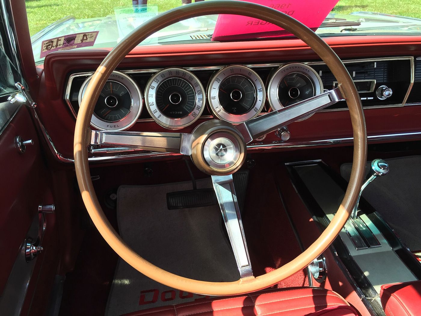 Dashboard of a 1966 Dodge Charger: four chrome-ringed round gauge pods behind a woodgrain-look steering wheel, red interior