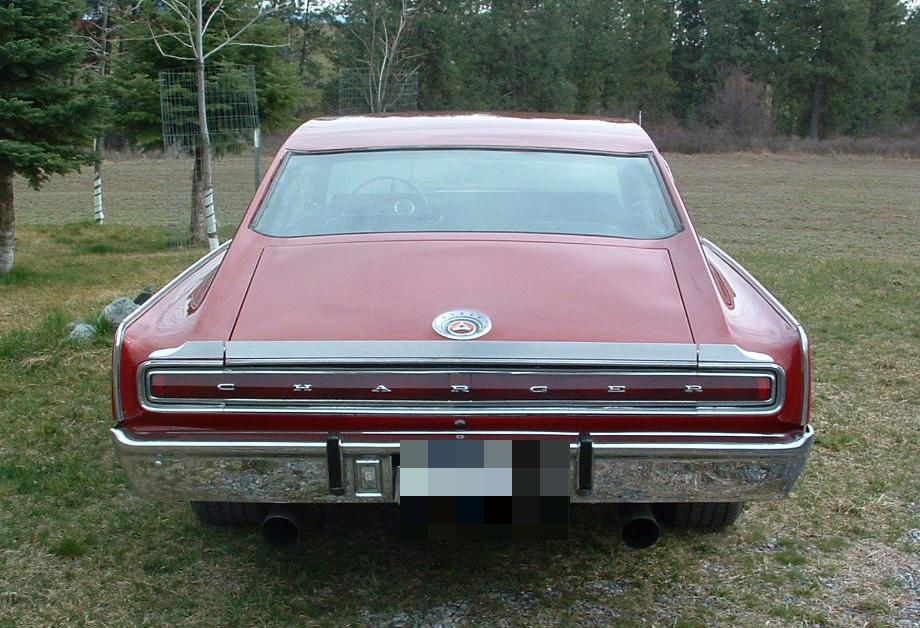 Rear of a maroon 1966 Dodge Charger fastback with the full-width taillamp band spelling out CHARGER